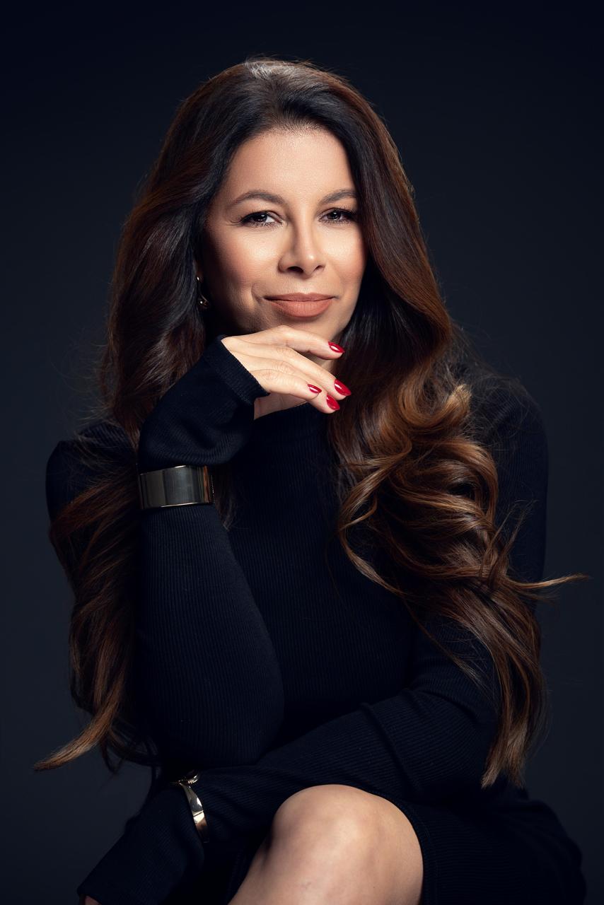 Simara Pires sentada com a mão no queixo, em retrato oficial